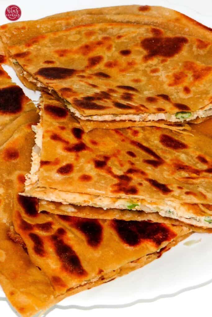 egg paratha showing layer of stuffed omelette in white plate