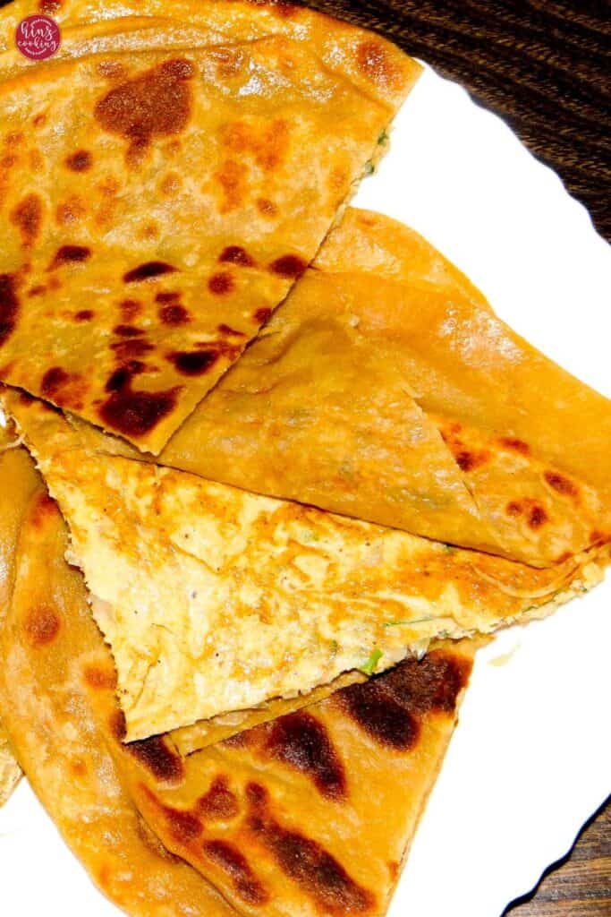 egg paratha showing layers of paratha on white plate