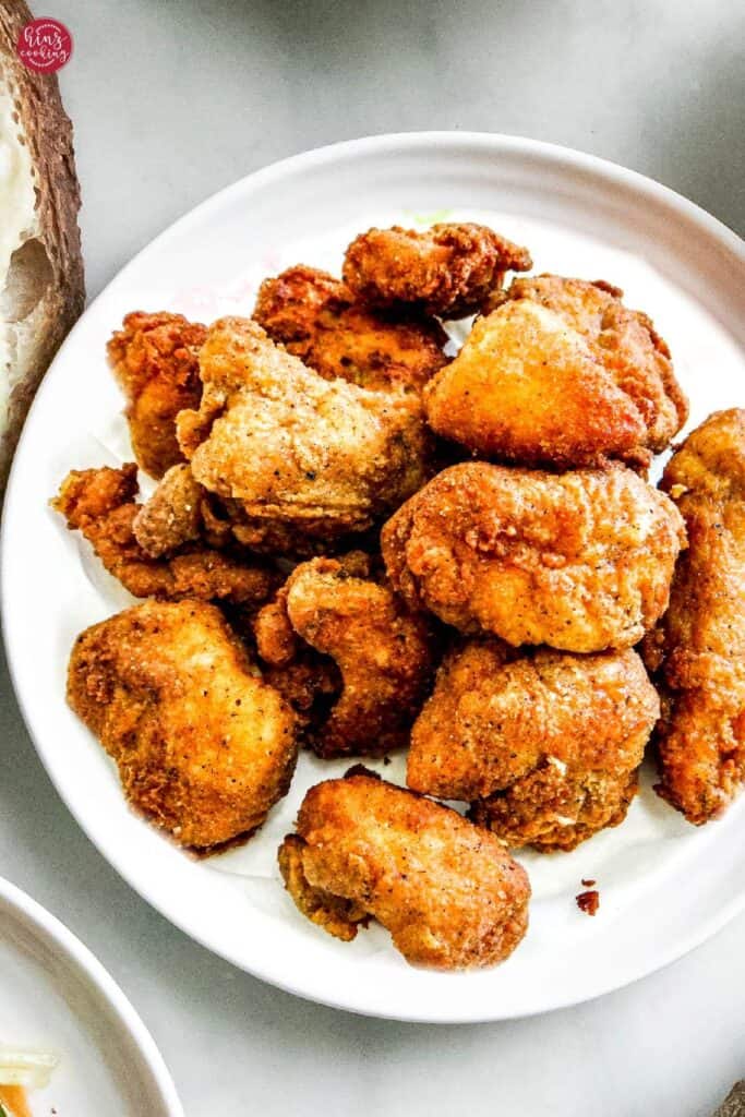 crispy and crunchy popcorn chicken pieces on a white plate.