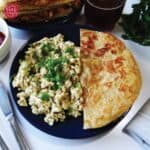 scrambled egg whites with bread slice in navy blue plate. White background.