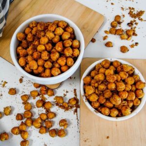 Air fryer roasted chickpeas in two white bowls on a white table, emphasizing their extremely crispy and crunchy texture.